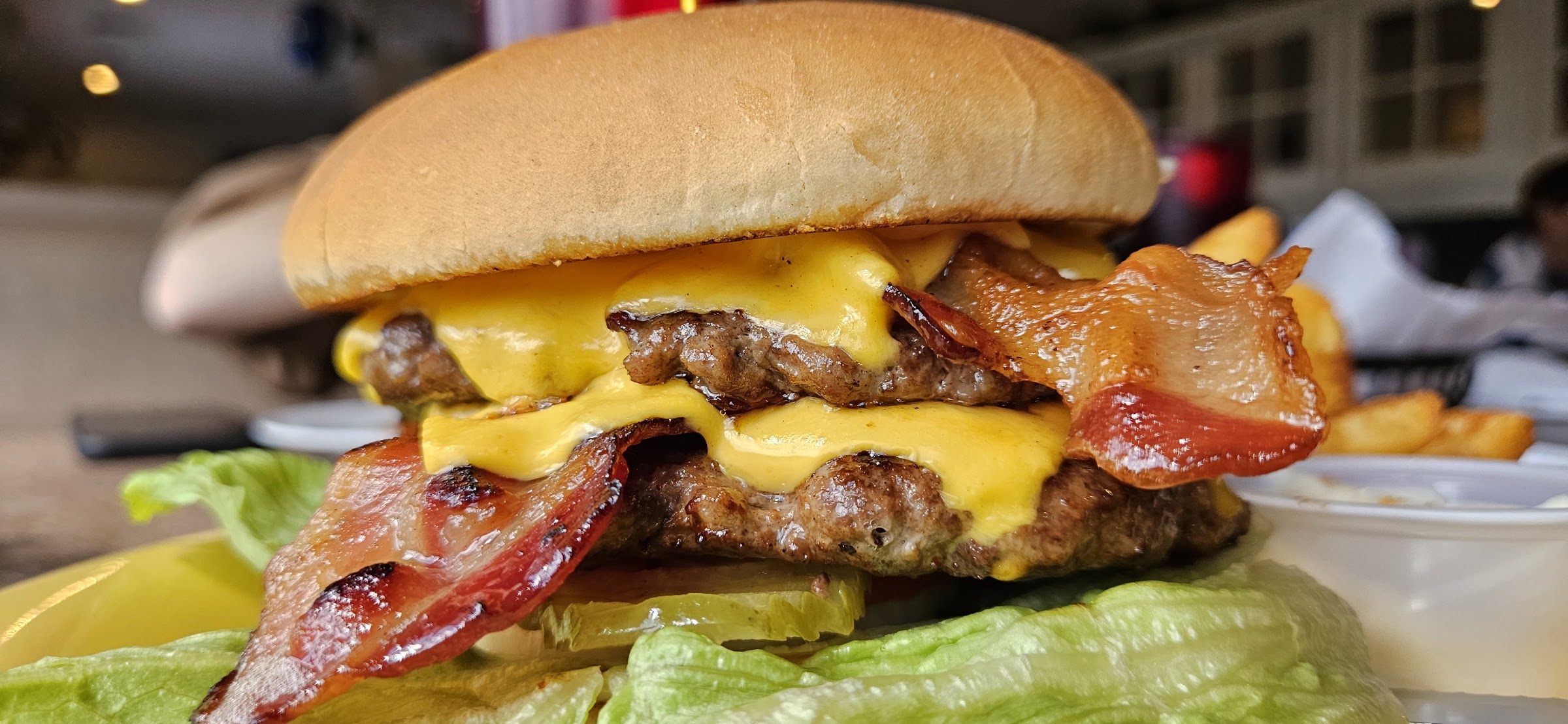 A double cheeseburger with golden fries on a vintage plate